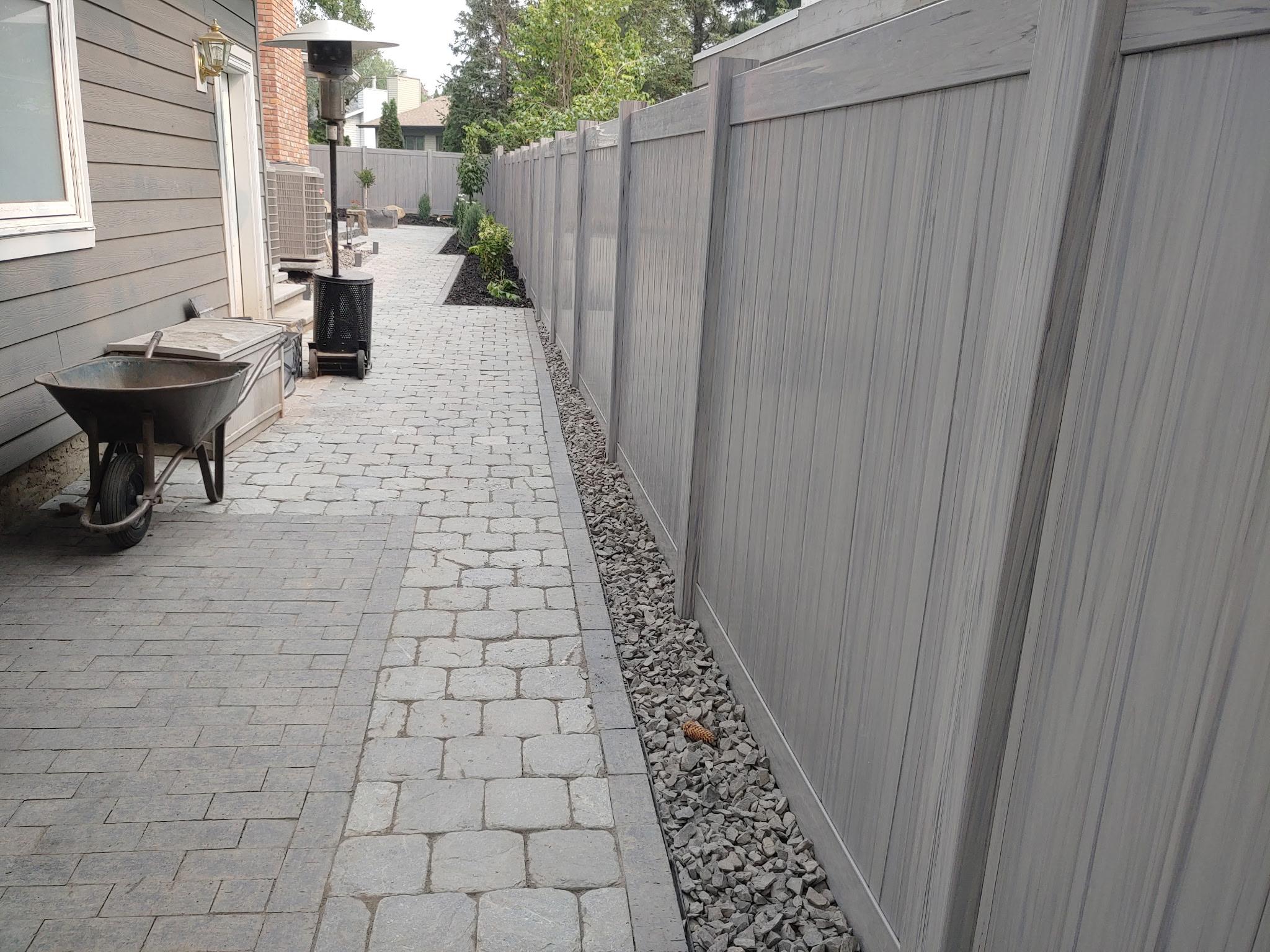 Cobblestone paver patio area between vinyl fence panels